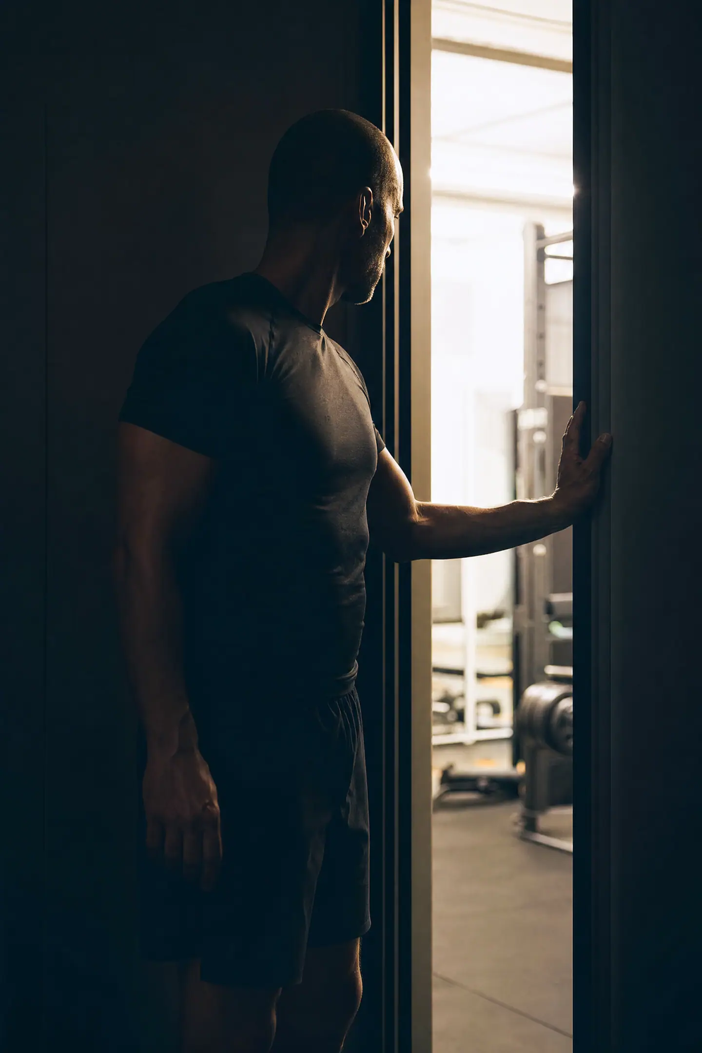 A man stepping back from a doorway in subdued light